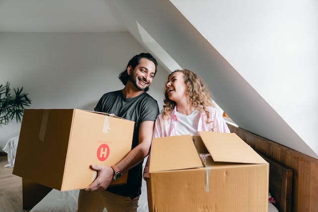 two%20tenants%20smiling%20while%20holding%20moving%20boxes